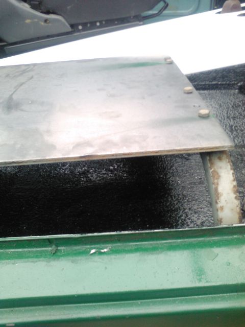1991 Ford Bronco - A metal plate is secured with bolts in the bed of a green truck, with a portion of a seat visible above.