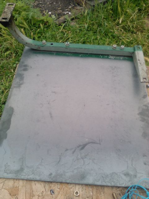 1991 Ford Bronco - A green metal bracket with visible bolts is shown against a flat surface and grassy background.