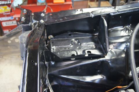1979 Ford Bronco - The engine bay of a vehicle is shown, with a focus on the battery tray and surrounding metalwork.
