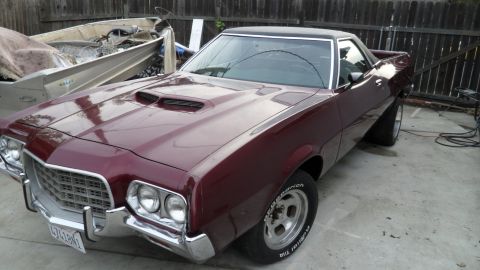 1972 Ford Ranchero - A 1972 Ford Ranchero in a deep maroon color is parked in a driveway, prominent hood scoops and classic aftermarket wheels.