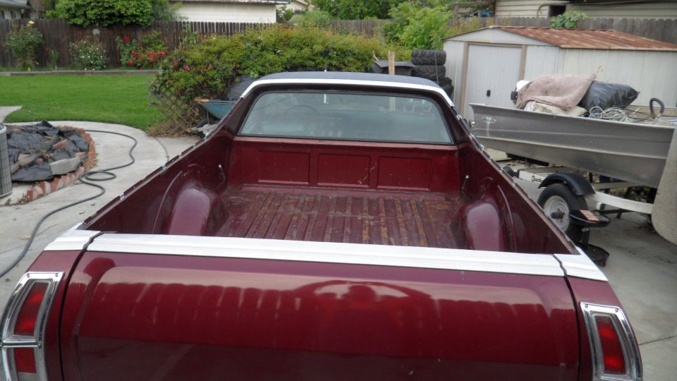 red pickup truck bed with white trim, boat on trailer in background