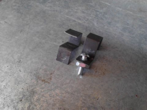 1990 Ford Bronco - Two metal brackets are shown, one secured with a bolt and washer, on a work surface.
