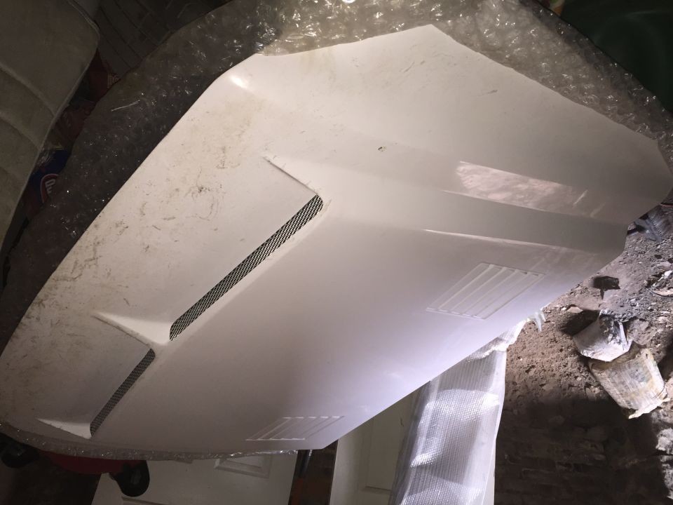 White fiberglass hood with dual vents and mesh inserts laid flat in a workshop