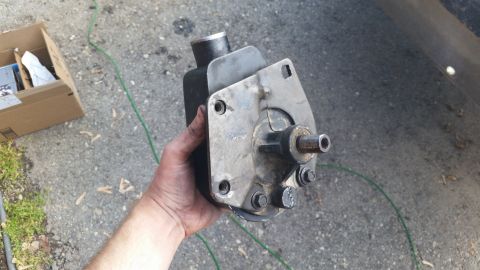 1981 Ford Bronco - Power steering pump removed from a vehicle, held in hand outdoors.