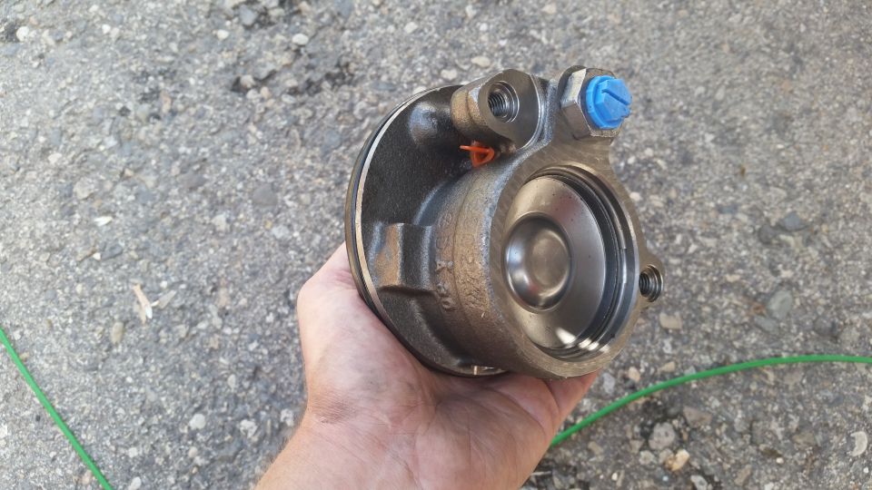 Brake caliper part held in hand, showing internal piston and blue cap
