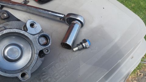 1981 Ford Bronco - A socket wrench and a bolt sit next to a disassembled automotive component on a plastic surface.