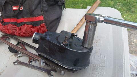 1981 Ford Bronco - Tools and a black automotive component are laid out on a surface, suggesting a repair or maintenance task.