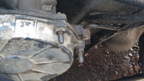 1981 Ford Bronco - A close-up view of a greasy automotive transmission part, showing bolted connections and textured metal surfaces.
