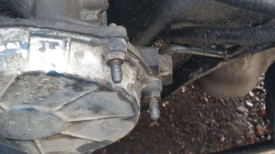 Close-up of a greasy, metallic automotive transmission housing with bolts