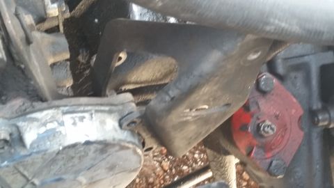 1981 Ford Bronco - Close-up view of an engine bracket and a red component, likely part of a vehicle's mechanical system.
