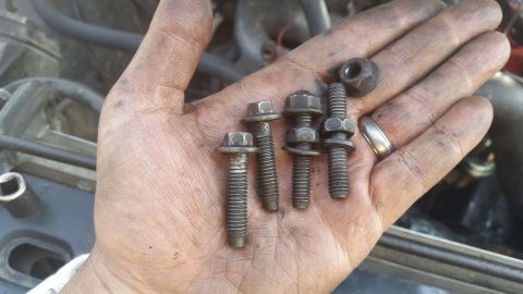 1981 Ford Bronco - A hand holds several bolts and a nut, with the Supermotors logo visible in the background.