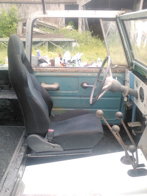 1991 Ford Bronco - The interior of a vintage SUV is visible, a bucket seat, steering wheel, and multiple gear shifters.