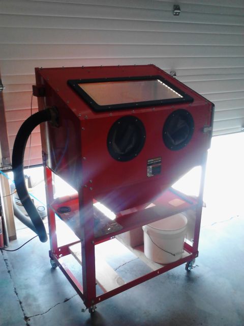 1990 Ford Bronco - A red sandblaster cabinet sits on a wheeled cart in a garage, ready for use.