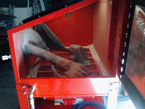 1990 Ford Bronco - Interior view of a red sandblaster cabinet, showing gloves and a metal component being worked on.