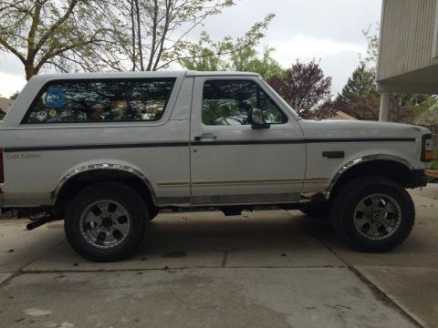 1995 Ford Bronco - A white Ford Bronco SUV is parked on a driveway, viewed from the side.