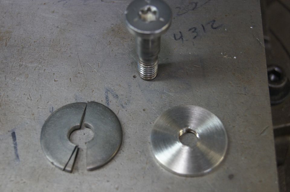 Bolt and two washers, one split, on a metal surface with handwritten numbers
