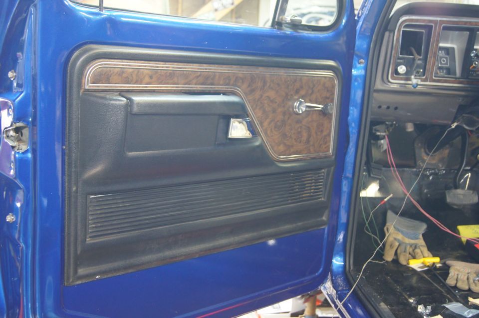 1979 Ford Bronco interior door panel with woodgrain trim and dashboard showing wiring