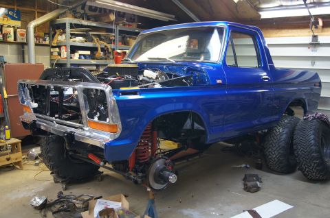 1979 Ford Bronco - A blue 1979 Ford Bronco is undergoing repairs in a garage, with its hood open and front end partially dismantled.