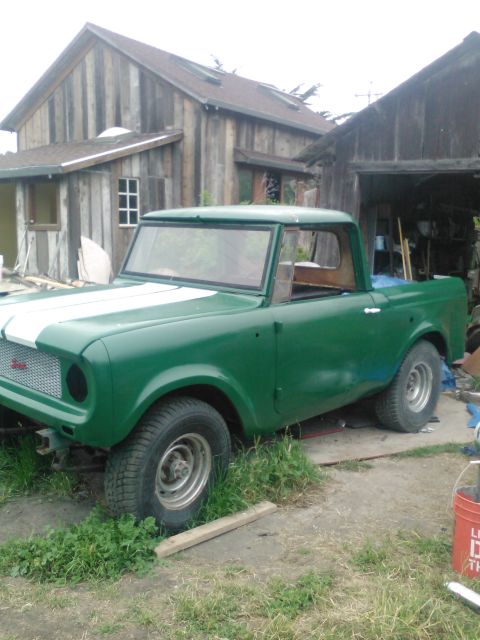 1991 Ford Bronco - This vintage International Harvester Scout pickup truck is green with white racing stripes and appears to be undergoing restoration.