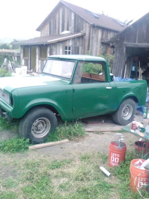 1991 Ford Bronco - A green pickup truck sits in a grassy area next to a wooden building.