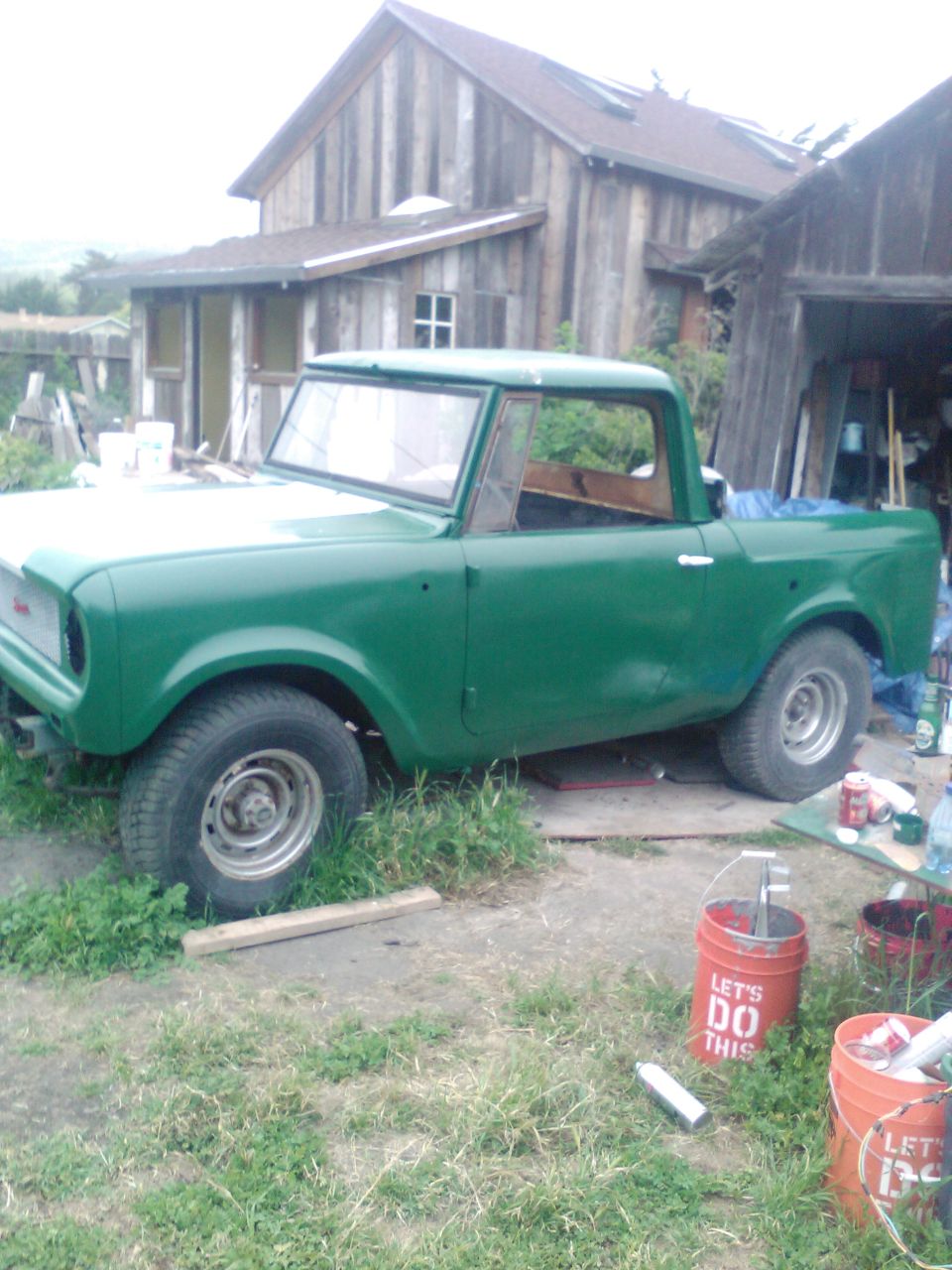 Green pickup truck with a white hood, parked outdoors on grass