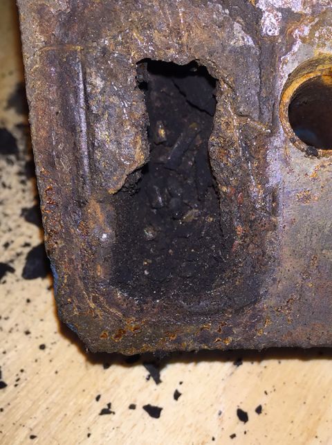 1978 Ford Bronco - This heavily corroded metal component displays significant rust and a large opening revealing accumulated debris within.