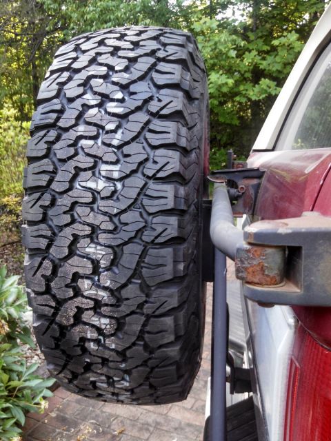 1995 Ford Bronco - Spare tire with aggressive tread pattern mounted on a vehicle's rear carrier.