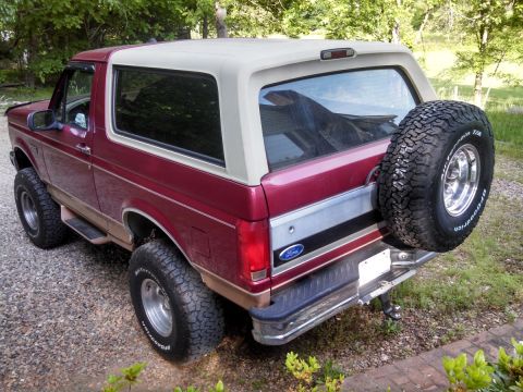 1995 Ford Bronco - The rear view of a red Ford Bronco, showing its spare tire mounted on the tailgate.