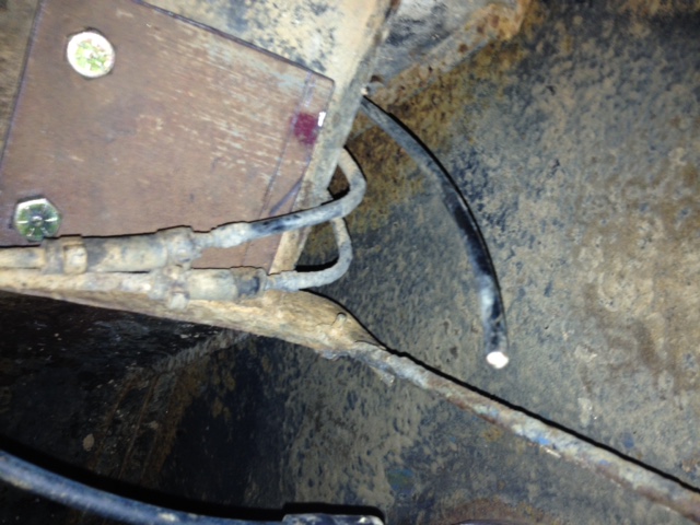 close-up of rusty brake lines and metal plate on vehicle undercarriage