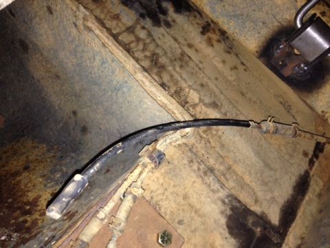 1973 Ford Bronco - The underside of a vehicle shows a cable running across rusty metal components.