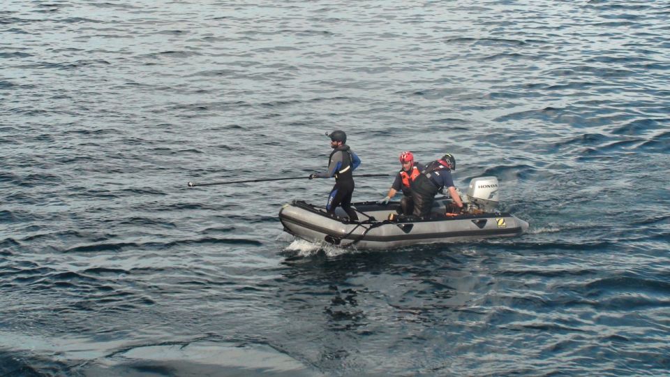 Inflatable boat with three people and a Honda outboard motor on choppy water