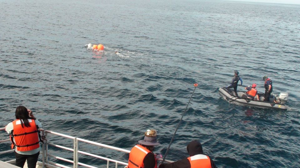 Inflatable boat with people, fishing rod, and buoys in the water