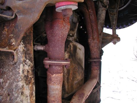 1990 Ford Bronco - Underside view of heavily rusted exhaust system parts, including pipes and flanges.