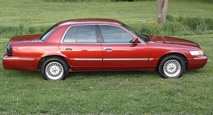 1999 Mercury Grand Marquis - Red 1999 Mercury Grand Marquis parked on grass with a flat rear tire.
