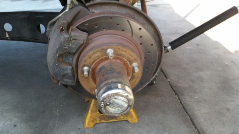 1992 Ford Bronco - Close-up of a vehicle's front wheel hub and brake assembly, supported by a jack stand.