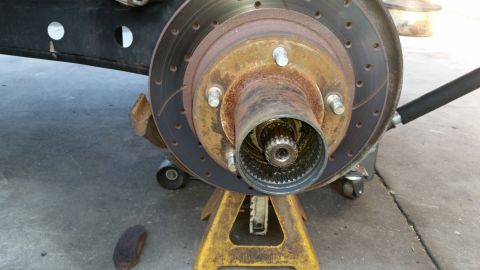 1992 Ford Bronco - Front wheel hub and brake rotor assembly on jack stands, with visible splines inside the hub.