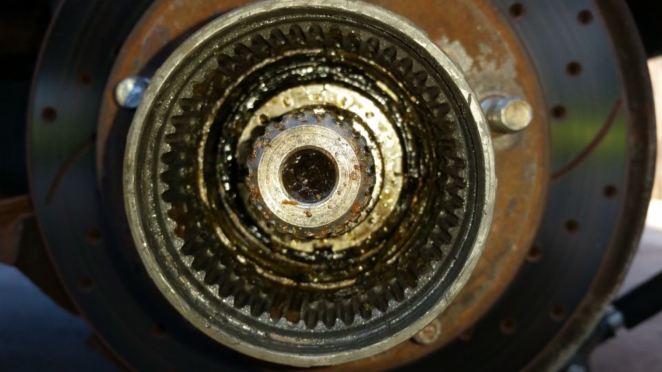 close-up of a greasy, toothed locking hub assembly with a brake rotor visible behind it