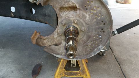 1992 Ford Bronco - Close-up of a corroded 1992 Ford Bronco front wheel hub assembly, supported by yellow jack stands.