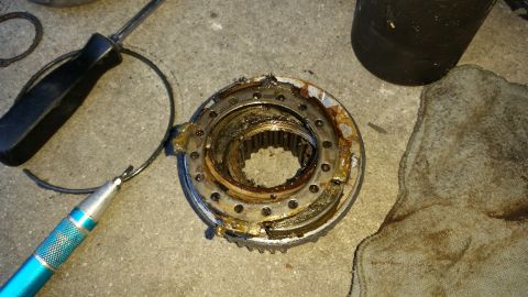 1992 Ford Bronco - A worn-out manual locking hub assembly lies on the ground next to a screwdriver and a pick tool.