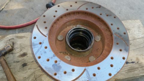 1992 Ford Bronco - A close-up of a brake rotor, showing wear and rust, with a hammer nearby.
