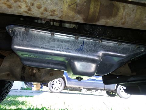 1996 Ford Bronco - The underside of a vehicle shows the oil pan and transmission, with another vehicle in the background.