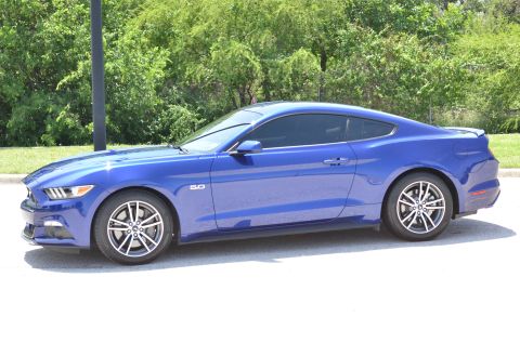 2015 Ford Mustang - A blue 2015 Ford Mustang is shown from the side, a '5.0' badge on the fender.