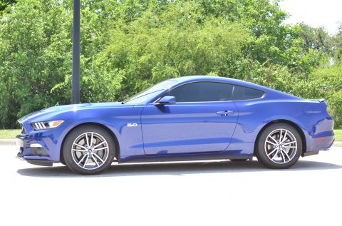 2015 Ford Mustang - A blue 2015 Ford Mustang coupe is shown from the side, with a '5.0' badge visible on the fender.