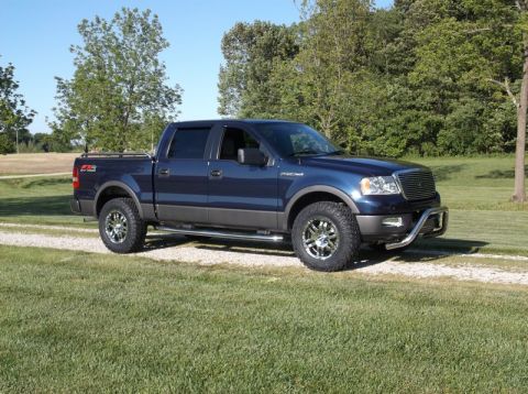 2005 Ford F-150 - A blue Ford F-150 pickup truck is shown from a three-quarter front view on a gravel path.