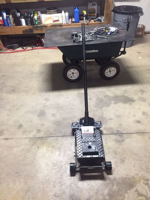 1982 Ford Bronco - Garage scene with a floor jack and a utility cart holding tools.