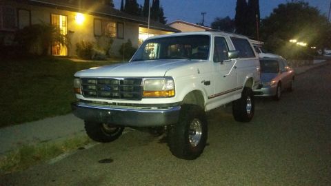1992 Ford Bronco - A white 1992 Ford Bronco is parked on a residential street at dusk.