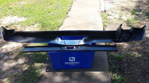 1976 Ford Ranchero - A vehicle's rear bumper and mounting bracket are displayed outside, placed on a blue recycling bin.