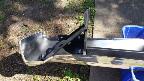 1976 Ford Ranchero - A chrome rear bumper assembly with a black metal bracket is shown outdoors on the ground.
