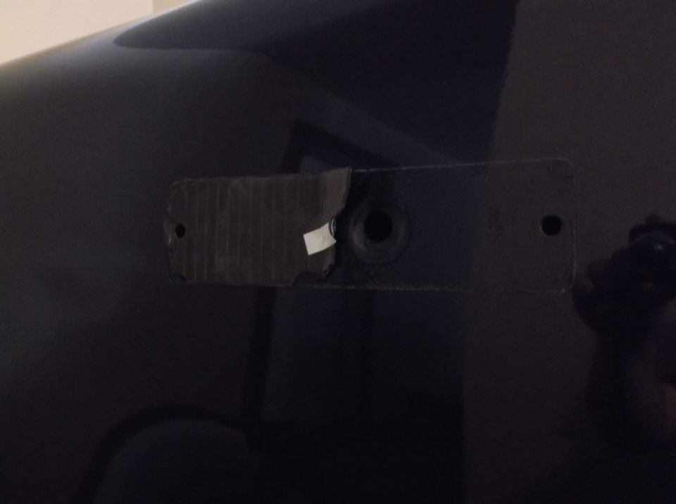 Black Ford F-150 rear bumper mounting bracket with torn tape and a hole