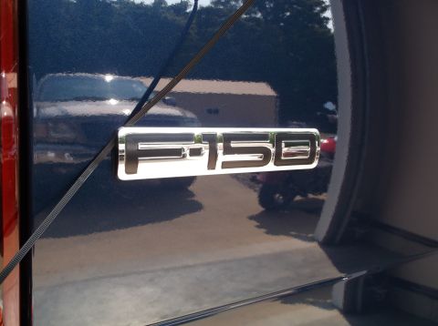2005 Ford F-150 - Close-up of the F-150 emblem on a dark blue Ford truck.